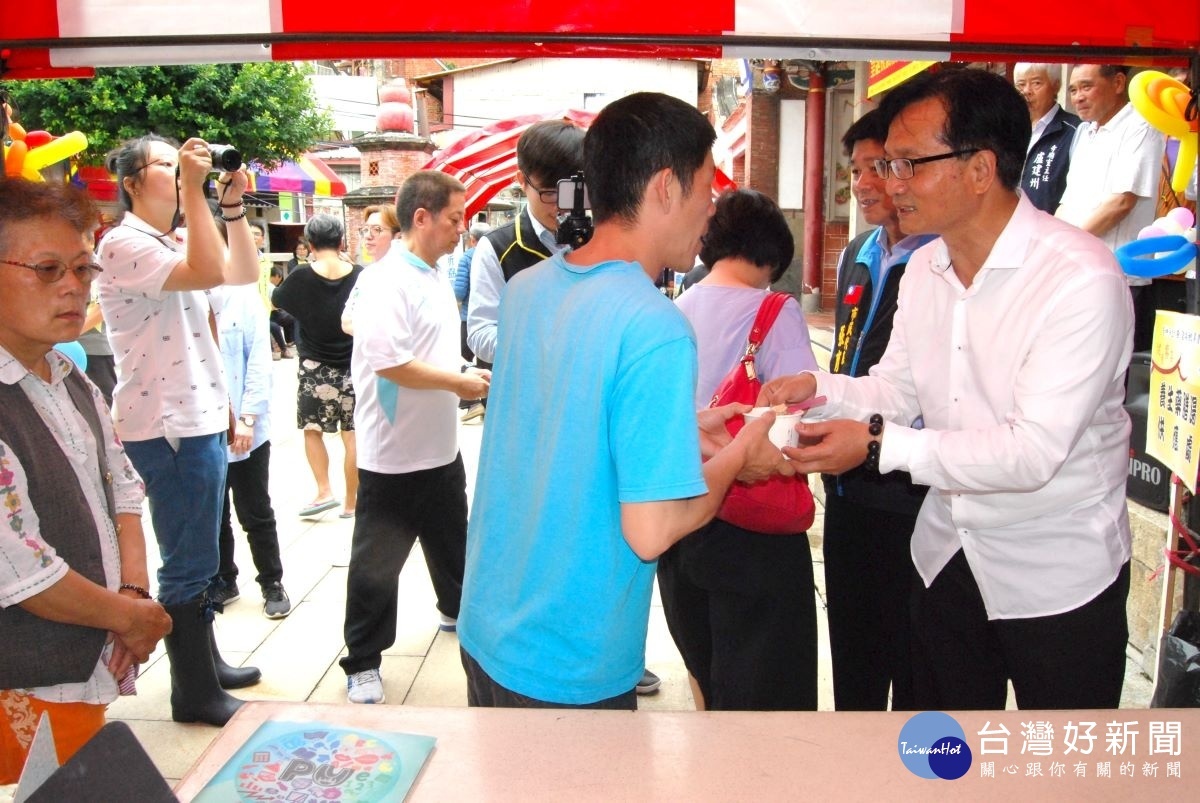 林世賢市長在慶安宮的健康饗宴活動中端送養生藥勝湯給民眾。