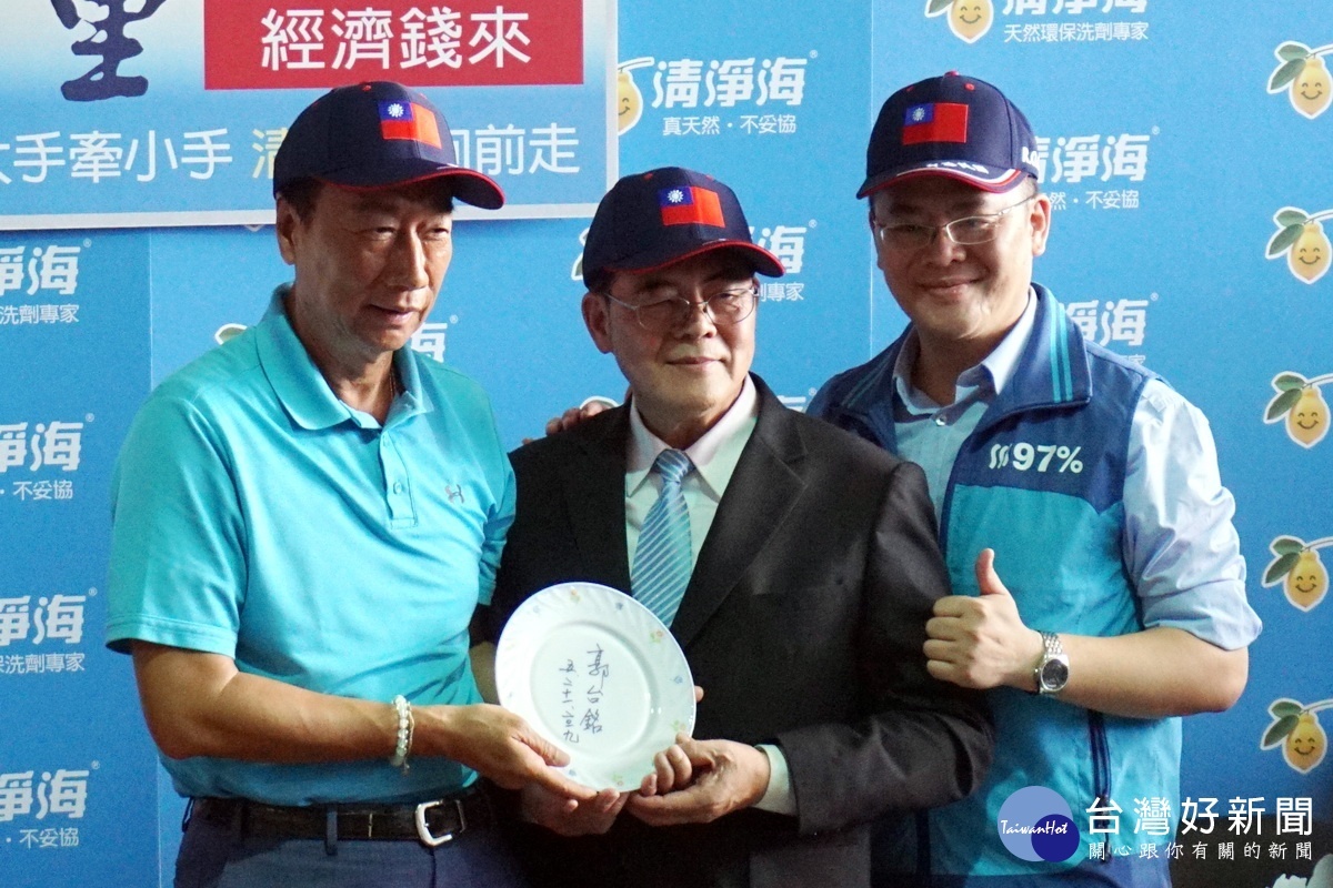 鴻海董事長郭台銘在自己洗過的盤子上簽名與清淨海董事長羅志禮合影留念。