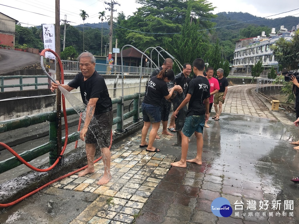 黑泥田中拔河結束後，參與活動人員在八堡圳旁的沖水站洗去田泥。(圖/記者王丰和攝)