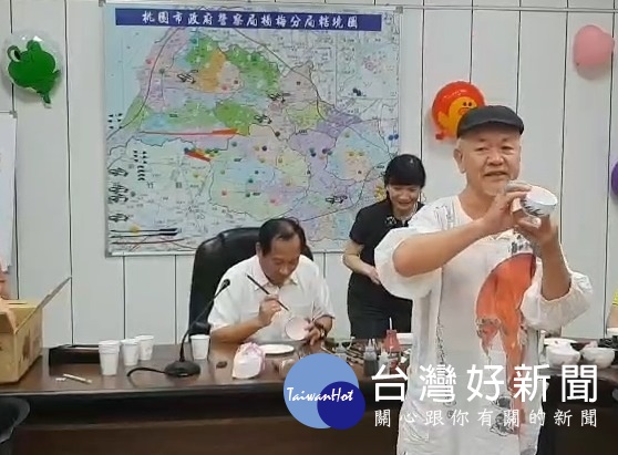 繪畫大師陳士侯(前)指導楊梅分局長林信雄(後)繪畫陶瓷茶杯