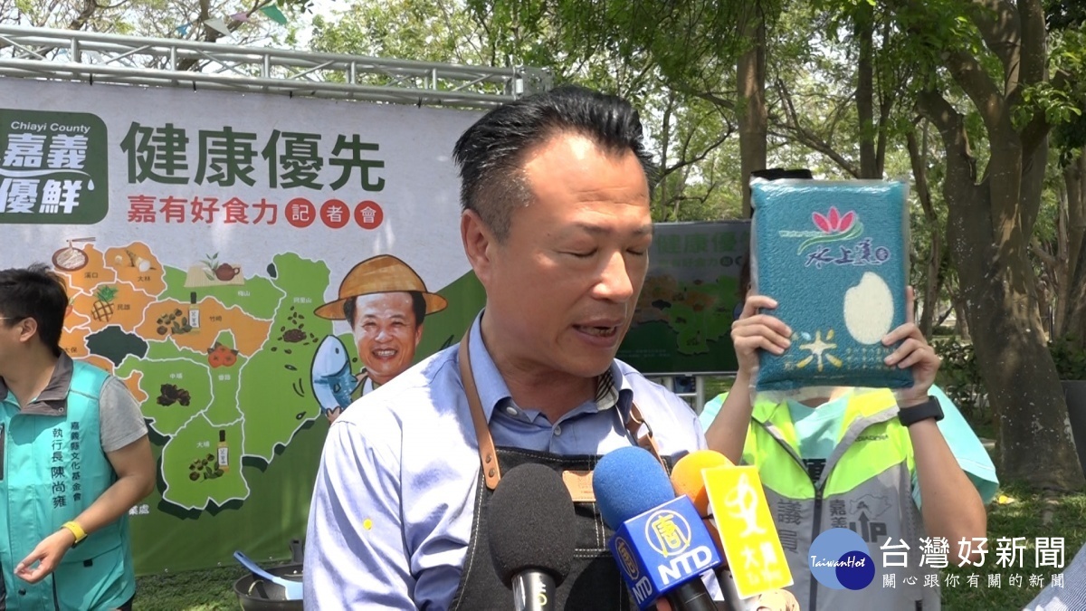 縣議員林緗亭手拿嘉義縣農特產,穿梭在縣長翁章梁身後賣力行銷/陳致愷翻攝