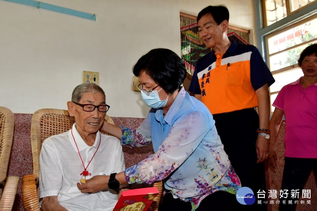 縣長王惠美為百歲人瑞鄭明白掛上金鎖片，祝福重陽節快樂。