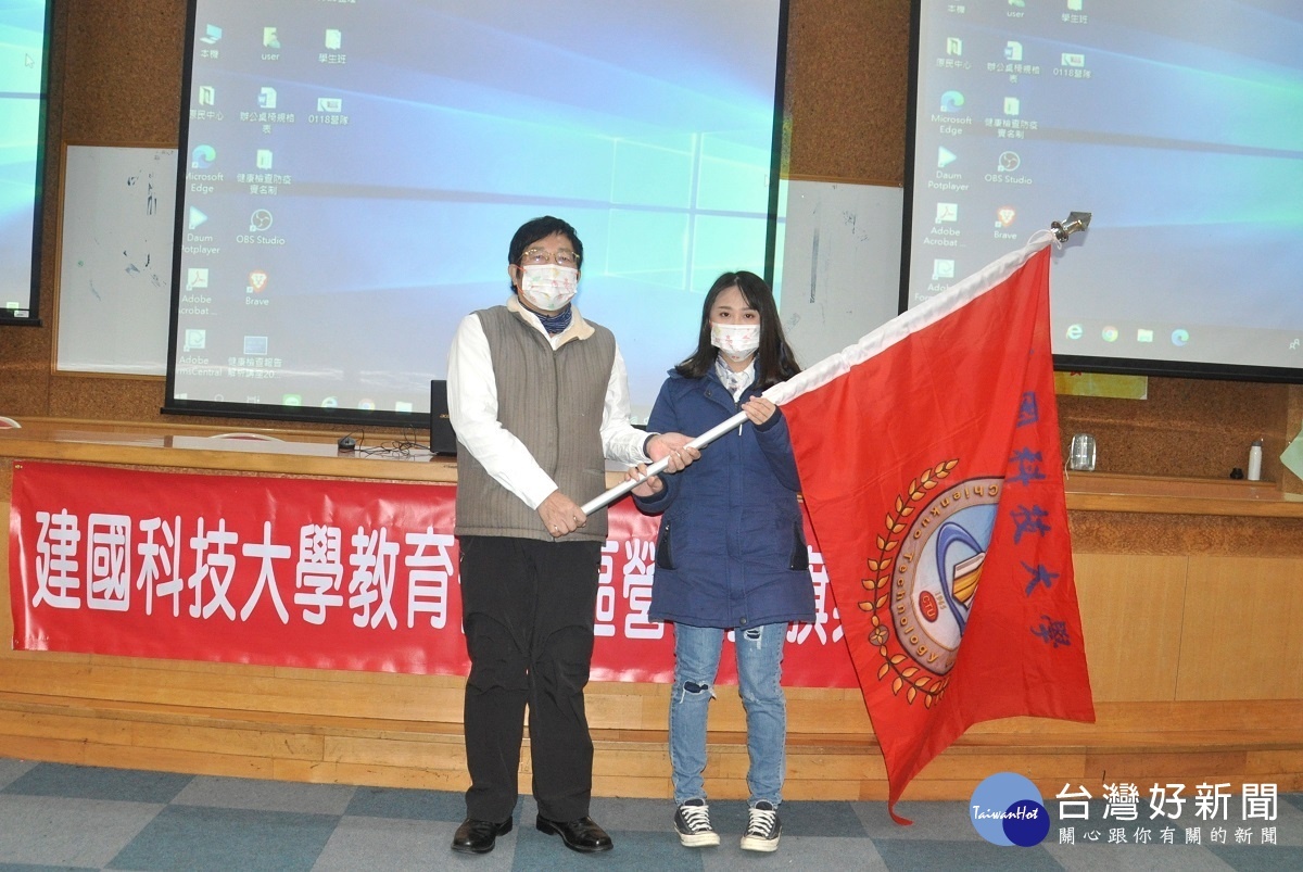 劉柄麟主任秘書授旗給行銷系學會代表，鼓勵她們要注意安全與健康。