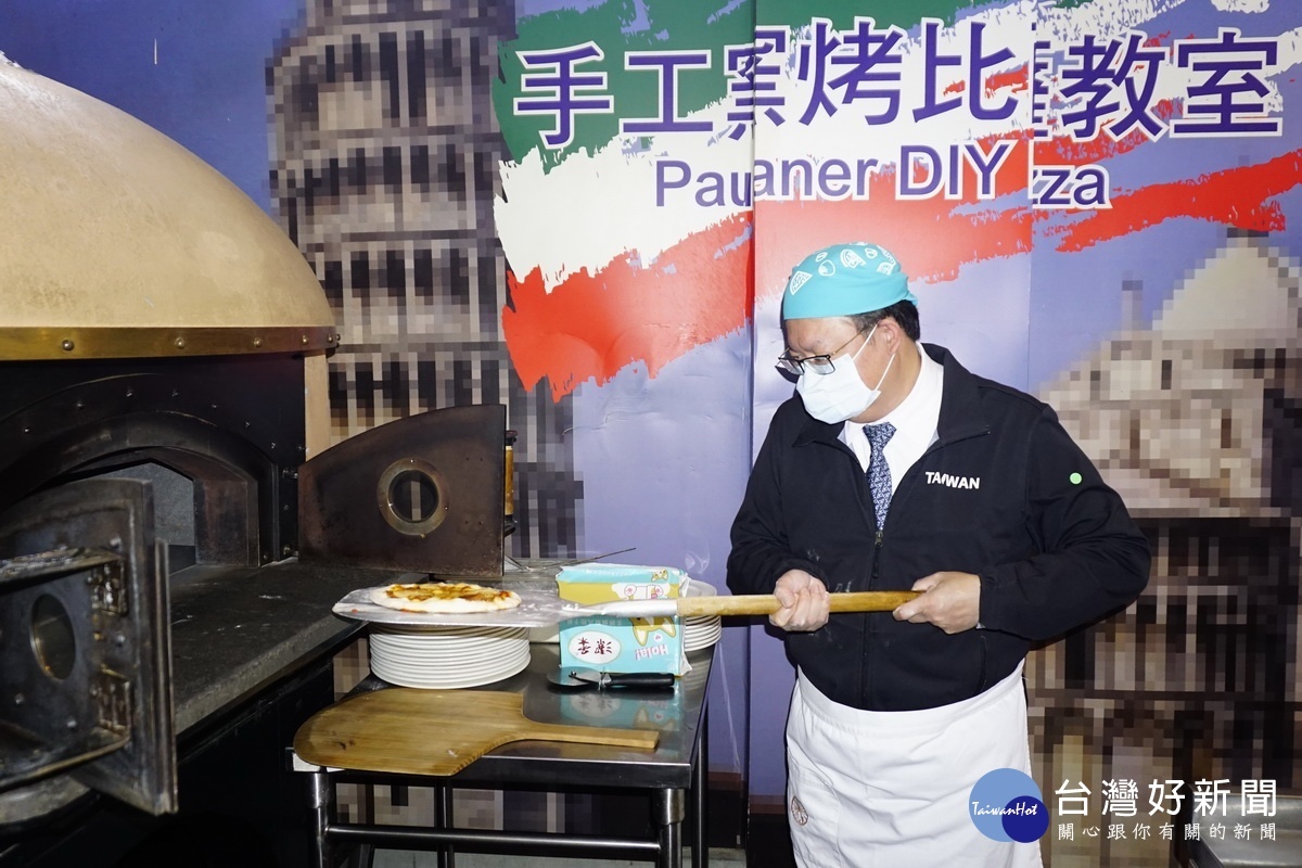 桃園市長鄭文燦行銷桃園觀光工廠，將手工製作的式Pizza放進窯爐內烘烤。