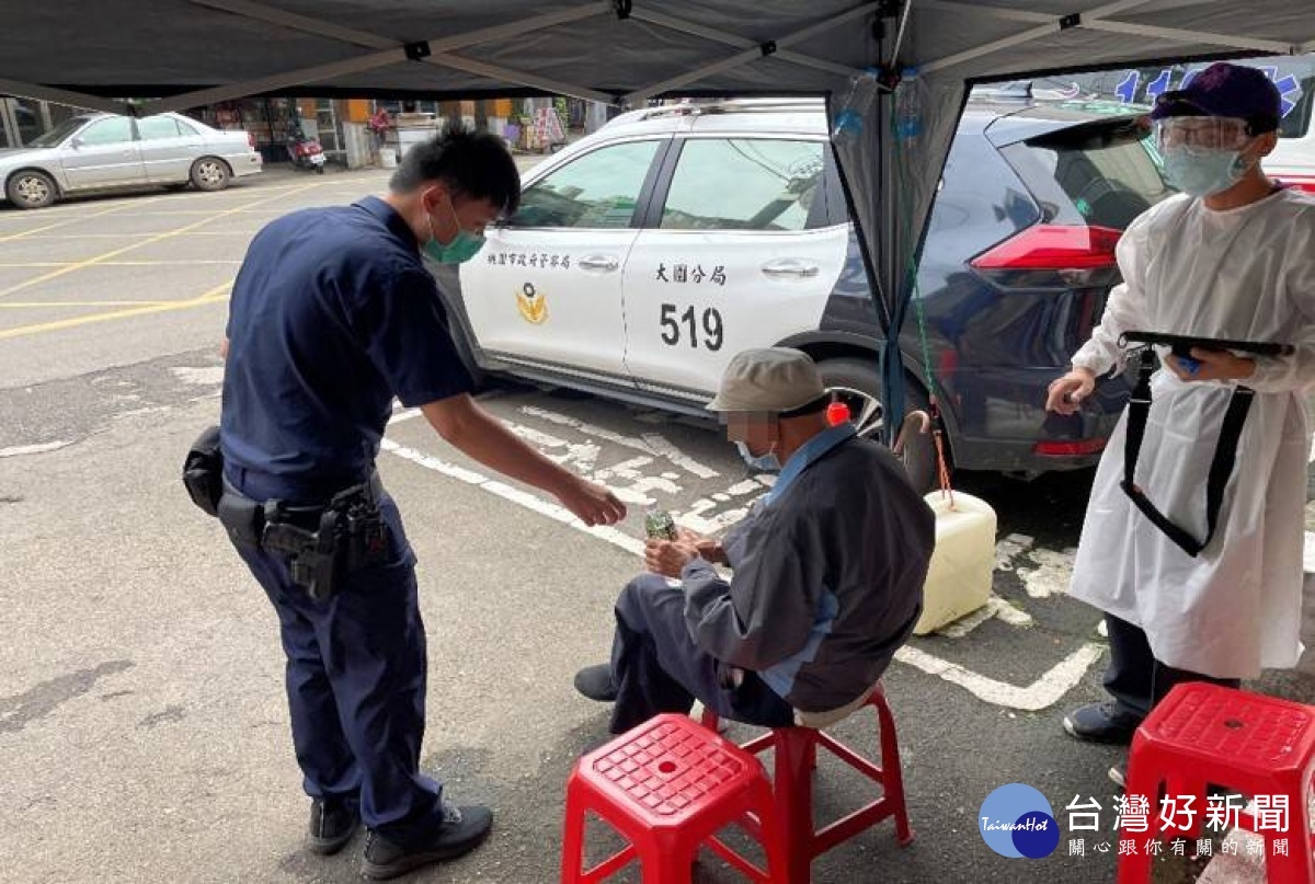 員警將老翁扶至派出所戶外帳棚下休息，並提供礦泉水讓他補充水分