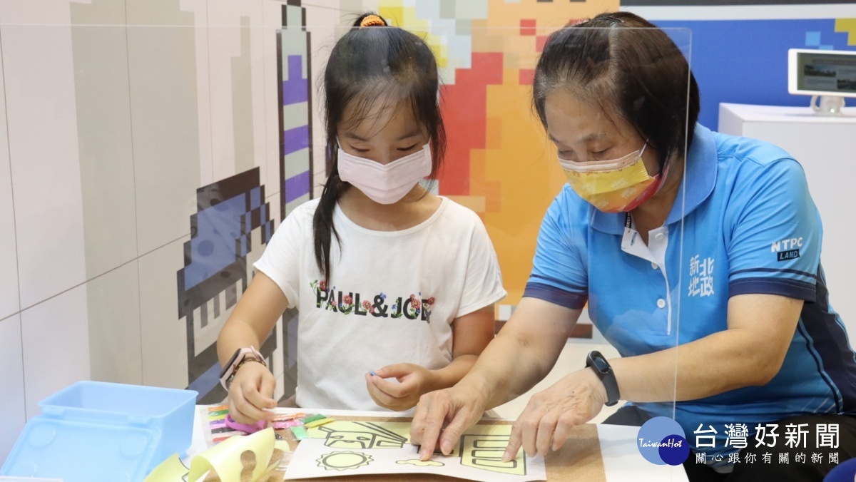 康秋桂局長(右)與小朋友共同繪製沙畫。