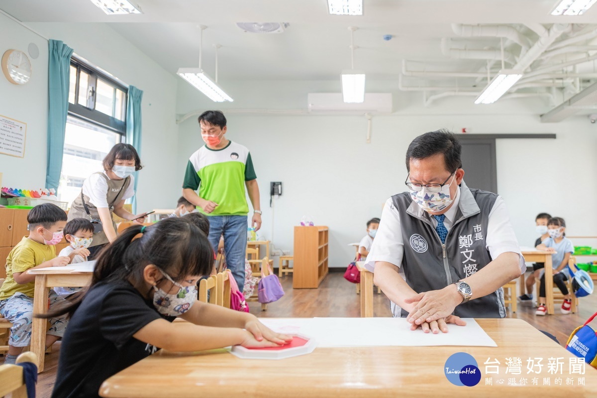 桃園市長鄭文燦視察國強非營利幼兒園，與小朋友們在圖畫紙上蓋下代表成長紀錄的手印。