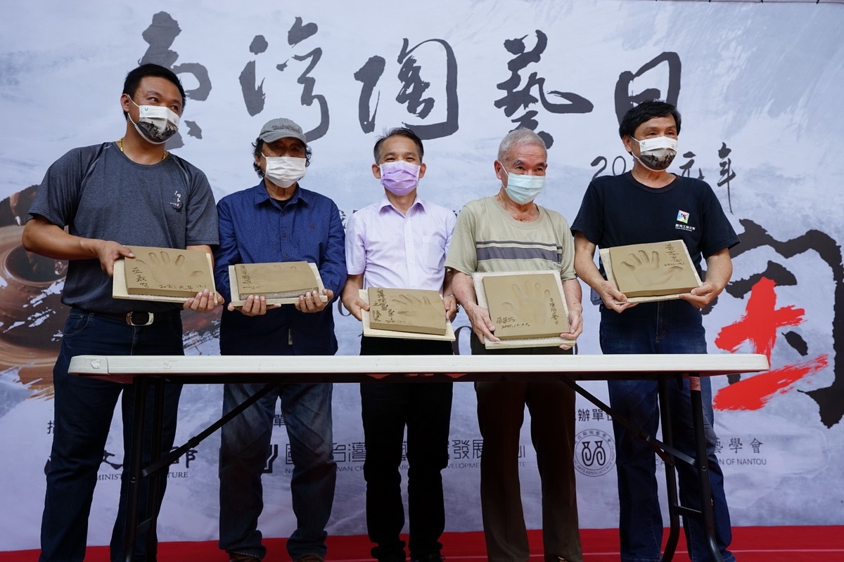 陶藝大師於陶板上蓋手印落款。（工藝中心提供）