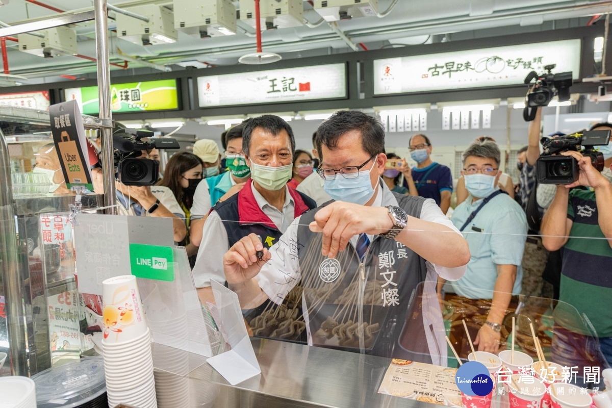 桃園市長鄭文燦於桃園區東門市場開幕活動中為攤商簽名。